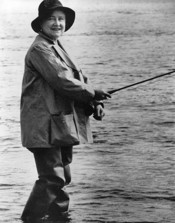 a woman dressed in hip waders standing in a river with a fishing rod in her hands