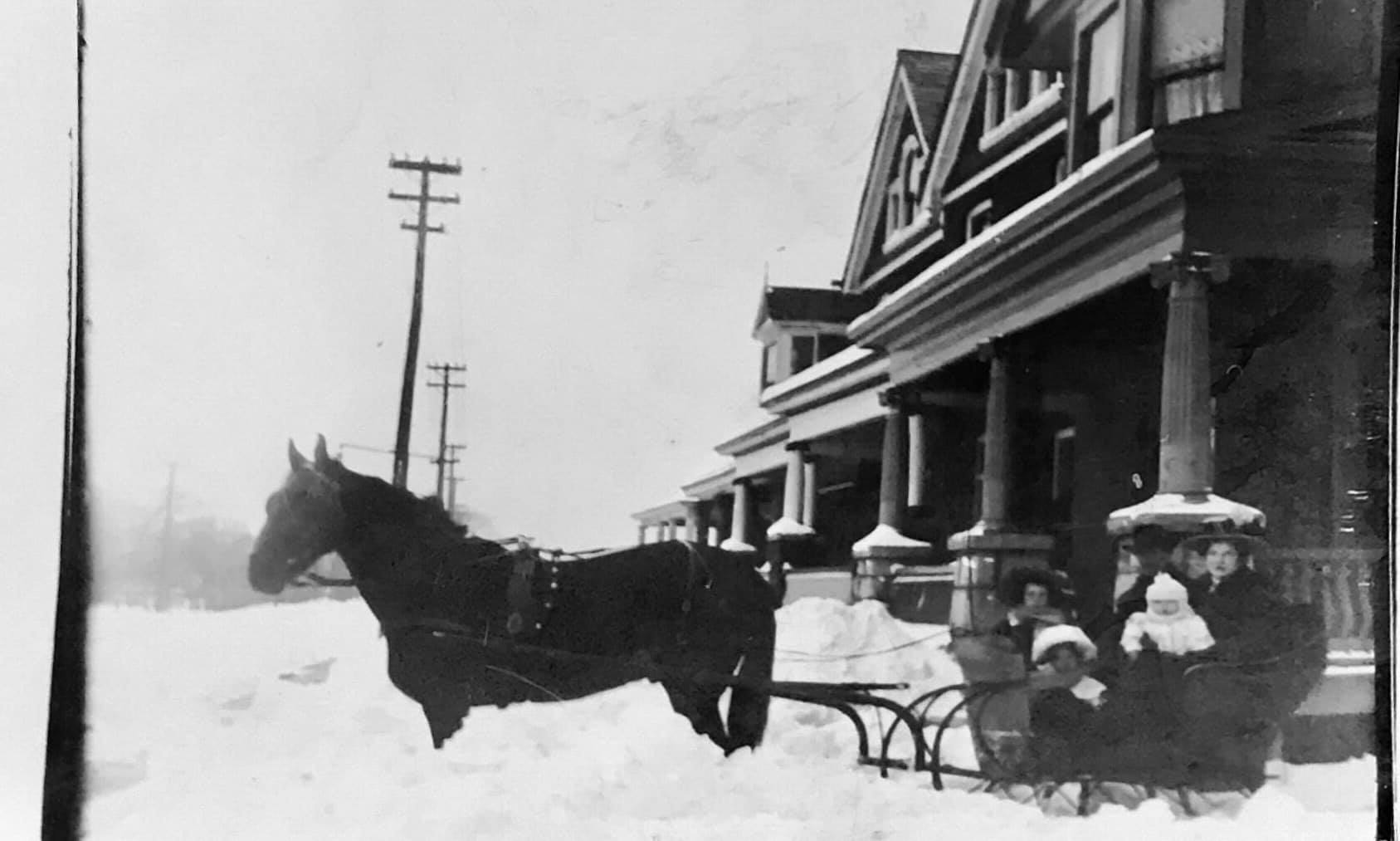 horse and buggy in front of a house in winter, early 1900s.
